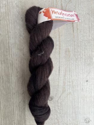 Strang Herzfasern No. 93 in einem tiefen, warmen Schokoladenbraun. Die Seide verleiht dem Garn einen feinen, matten Glanz. Das Garn wirkt weich, luxuriös und leicht flauschig.